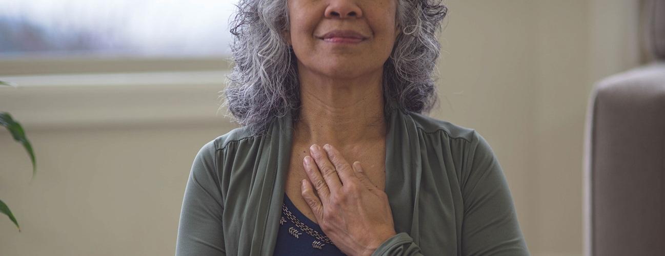 an older woman inhaling with her hand on her chest