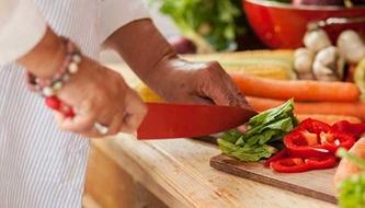 A woman chops vegetables.