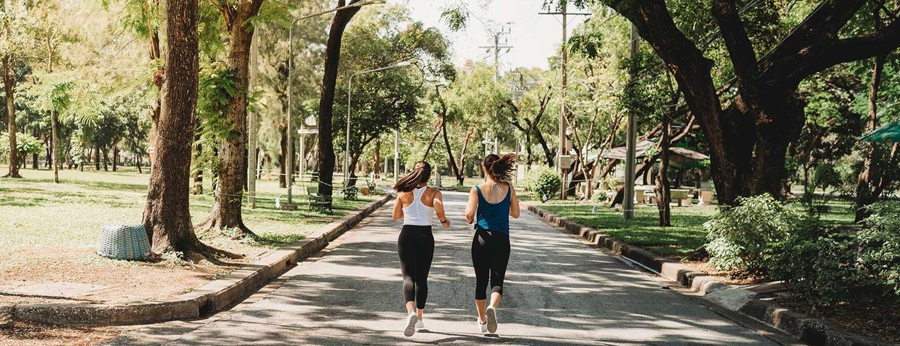 Two women jog together through a park.