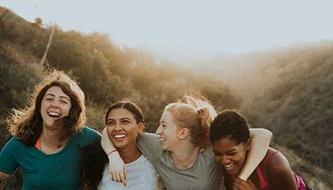 A group of female friends smile outside.