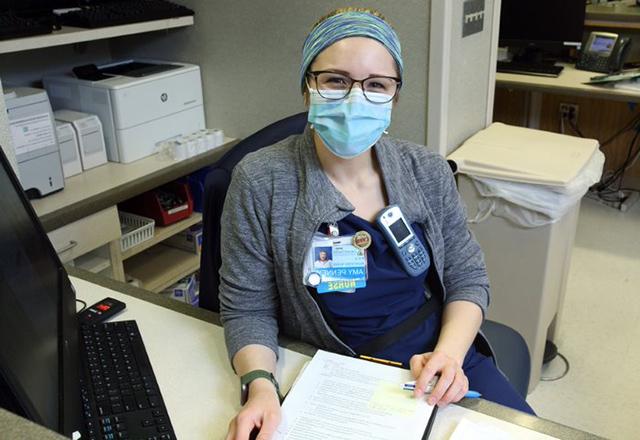 护士艾米·彭尼(Amy Penney)戴着口罩坐在她的办公桌前.